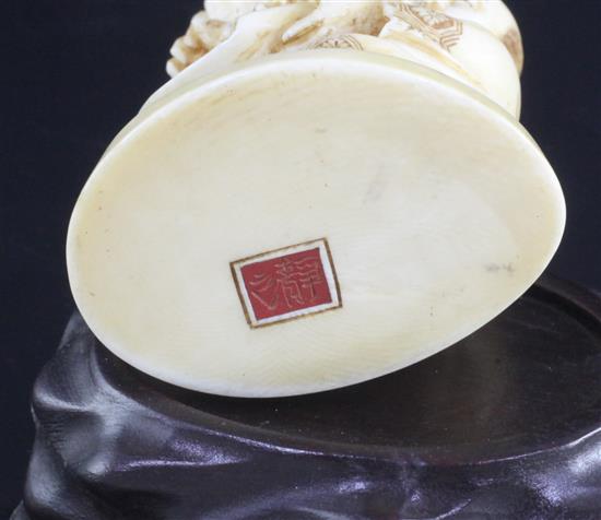 A Japanese ivory okimono of Kwannon standing upon a giant carp, early 20th century, 24.3cm, wood stand